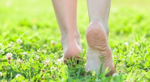 女性は草の上で靴なしで歩いている